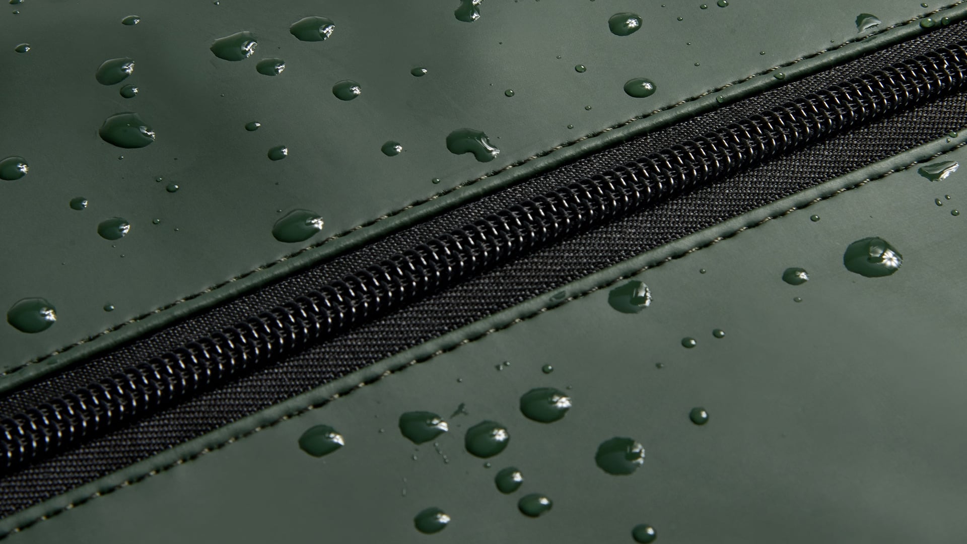 Gouttes d’eau perlant sur la toile déperlante verte du sac de sport Turenne Soft, de part et d’autre du zip